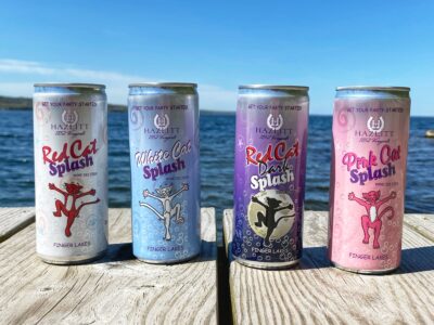 four cans of hard seltzer on the end of a dock overlooking a lake
